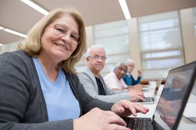 Group of senior adults using laptops for a digital learning session in a modern indoor setting.